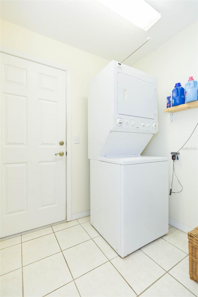 laundry area with stacked washer and dryer and light tile patterned floors