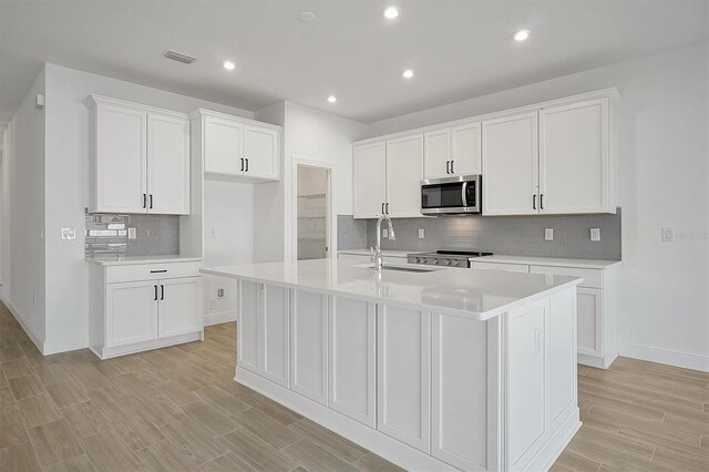 kitchen with a center island with sink, white cabinetry, and sink