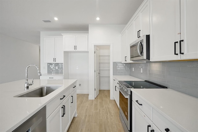 kitchen featuring backsplash, stainless steel appliances, sink, light hardwood / wood-style flooring, and white cabinetry