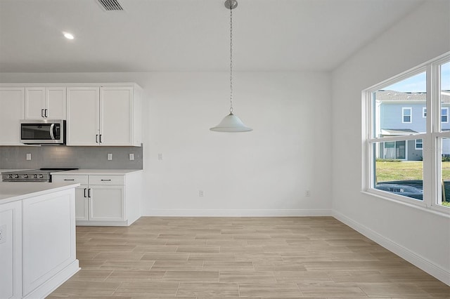 kitchen with white cabinetry, a healthy amount of sunlight, backsplash, pendant lighting, and appliances with stainless steel finishes