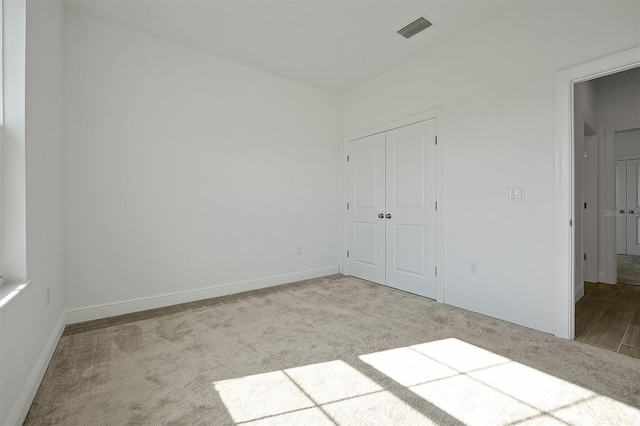 unfurnished bedroom with light carpet and a closet