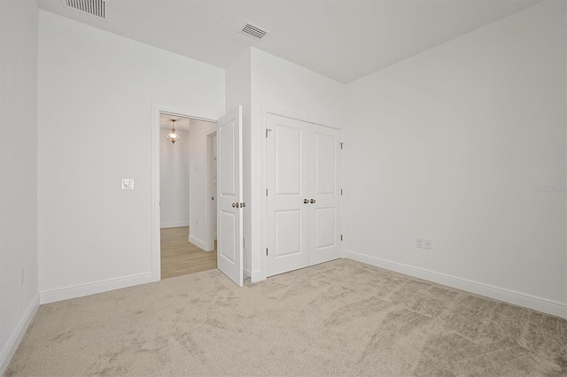 unfurnished bedroom featuring light colored carpet and a closet