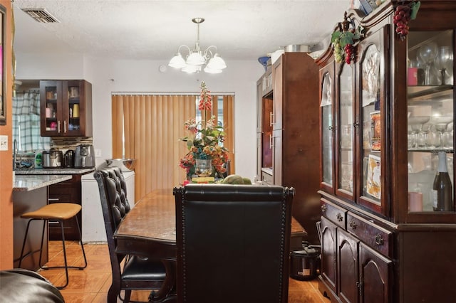 tiled dining room featuring an inviting chandelier and a textured ceiling