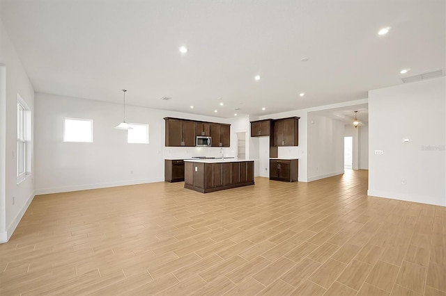 kitchen featuring dark brown cabinets, sink, pendant lighting, light hardwood / wood-style flooring, and a kitchen island