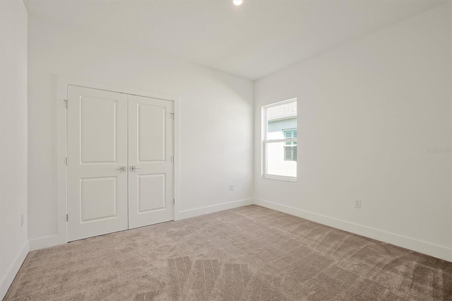 unfurnished bedroom featuring a closet and light colored carpet