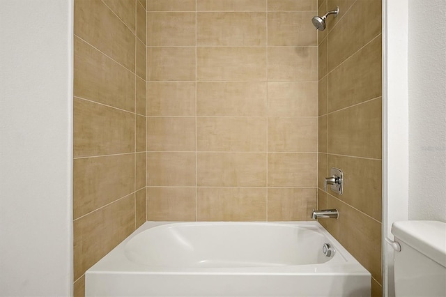 bathroom featuring tiled shower / bath combo and toilet