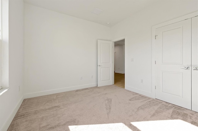 unfurnished bedroom featuring light colored carpet and a closet