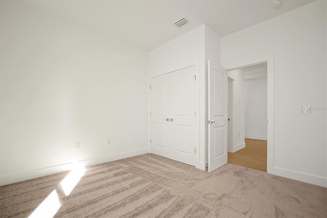 unfurnished bedroom with light colored carpet and a closet