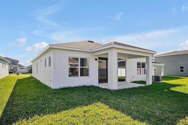 rear view of house with central air condition unit, a patio area, and a lawn