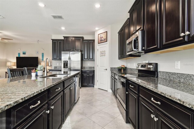 kitchen featuring light stone countertops, sink, stainless steel appliances, and ceiling fan