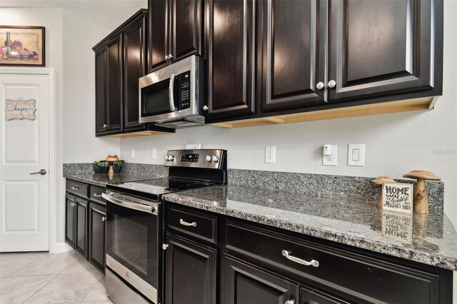 kitchen with appliances with stainless steel finishes, stone countertops, and light tile patterned floors