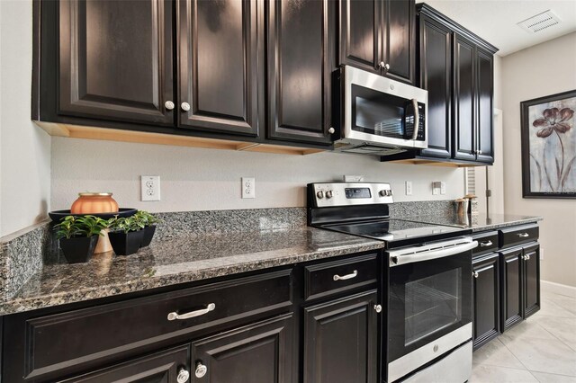 kitchen featuring stainless steel appliances, dark stone countertops, and light tile patterned floors