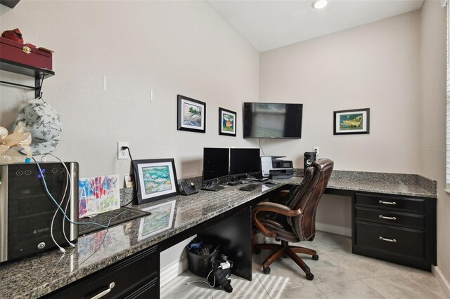 office space with lofted ceiling, built in desk, and light tile patterned floors