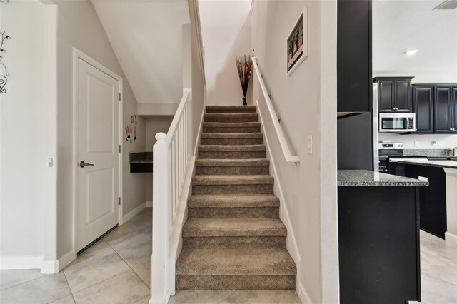 staircase featuring lofted ceiling and tile patterned floors