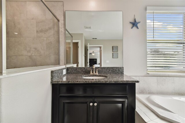 bathroom featuring vanity and tiled bath