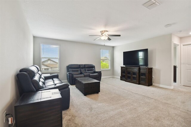 living room with a wealth of natural light, ceiling fan, and light carpet