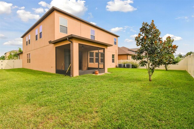 back of property featuring central air condition unit, a yard, and a sunroom