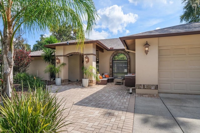 view of exterior entry featuring a garage and outdoor lounge area