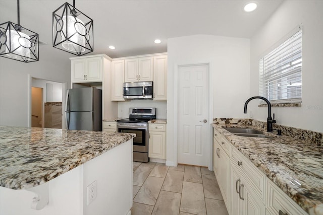 kitchen featuring light stone counters, sink, pendant lighting, and appliances with stainless steel finishes