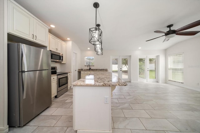 kitchen featuring a center island, hanging light fixtures, light stone countertops, appliances with stainless steel finishes, and french doors