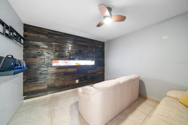 tiled living room with ceiling fan, wood walls, and a textured ceiling