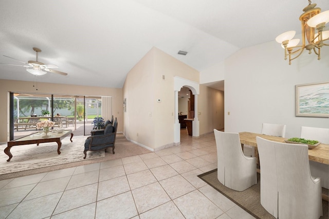 dining area with ceiling fan with notable chandelier, light tile patterned floors, and vaulted ceiling