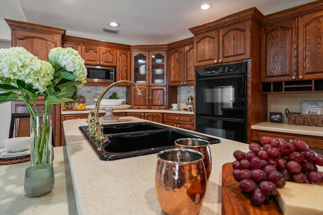 kitchen featuring sink, stainless steel microwave, double oven, and tasteful backsplash