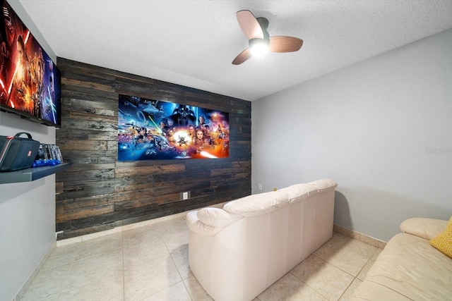 tiled home theater with ceiling fan, wood walls, and a textured ceiling