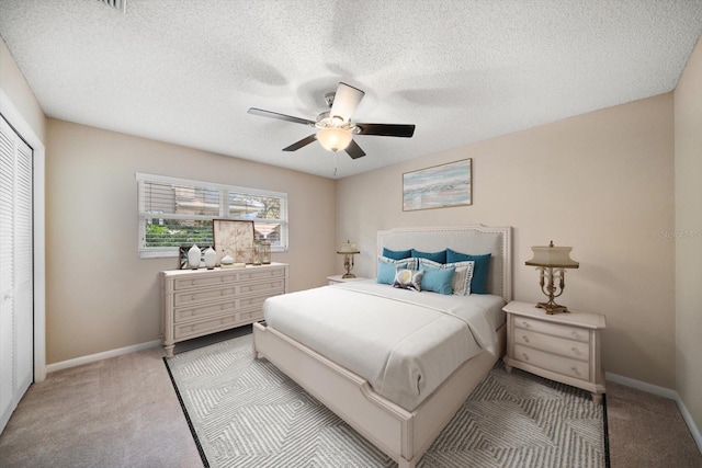 bedroom with ceiling fan, light colored carpet, a closet, and a textured ceiling