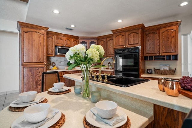 kitchen featuring stainless steel microwave, light countertops, dobule oven black, and a sink