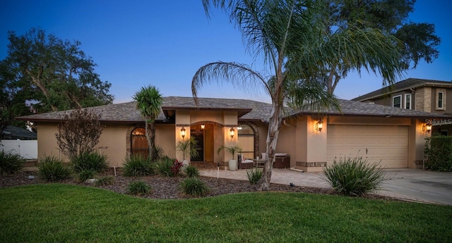 view of front of home with a garage, driveway, a front yard, and stucco siding