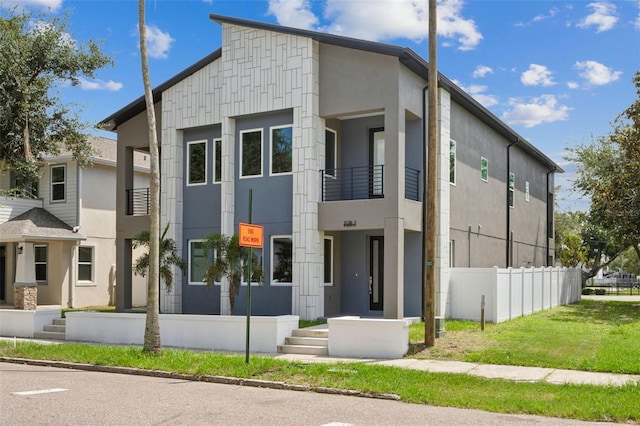 view of front facade with a balcony and a front lawn