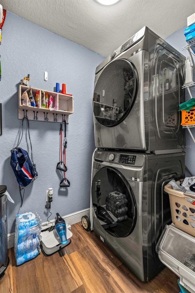 laundry area with stacked washer and dryer, a textured ceiling, and hardwood / wood-style floors