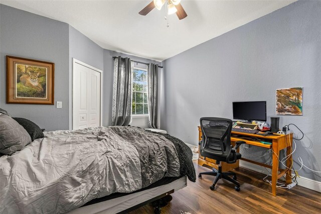 bedroom with dark wood-type flooring, ceiling fan, and a closet