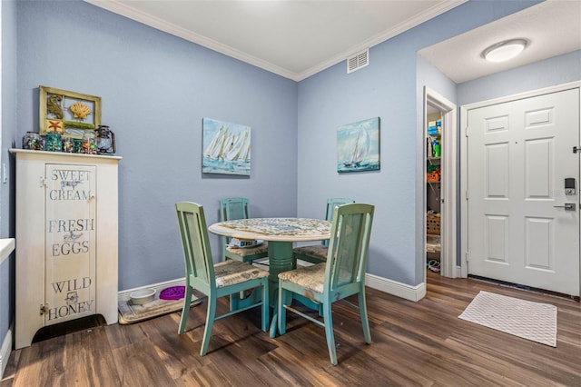 dining space with dark wood-type flooring and crown molding