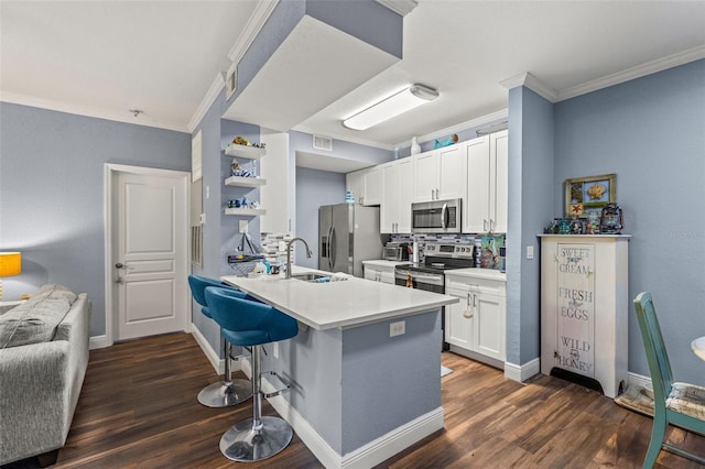 kitchen with a breakfast bar area, appliances with stainless steel finishes, kitchen peninsula, decorative backsplash, and white cabinets