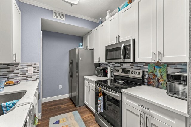 kitchen featuring stainless steel appliances, crown molding, dark wood-type flooring, white cabinets, and backsplash