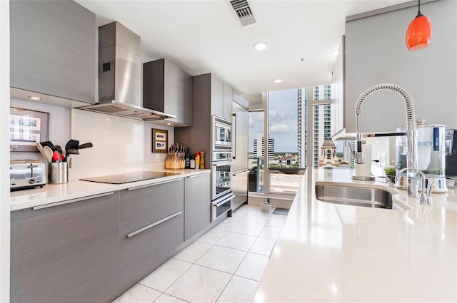 kitchen with sink, stainless steel appliances, gray cabinetry, and wall chimney range hood