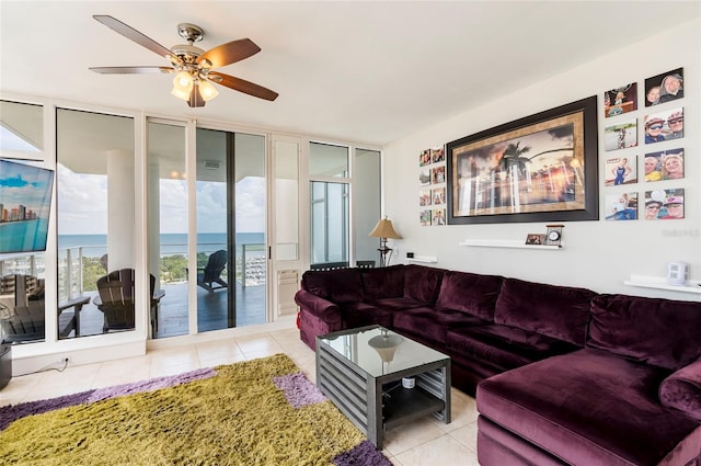 tiled living room featuring a water view, ceiling fan, and a wall of windows