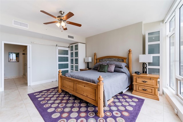 bedroom with light tile patterned floors, ceiling fan, and a barn door