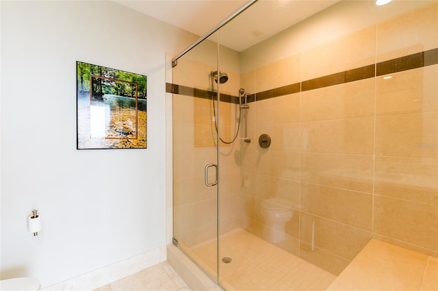 bathroom featuring toilet, a shower with shower door, and tile patterned floors