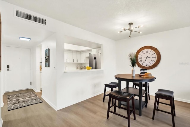 dining space featuring a notable chandelier, light hardwood / wood-style floors, and a textured ceiling