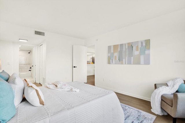 bedroom featuring ensuite bath, a closet, and hardwood / wood-style flooring