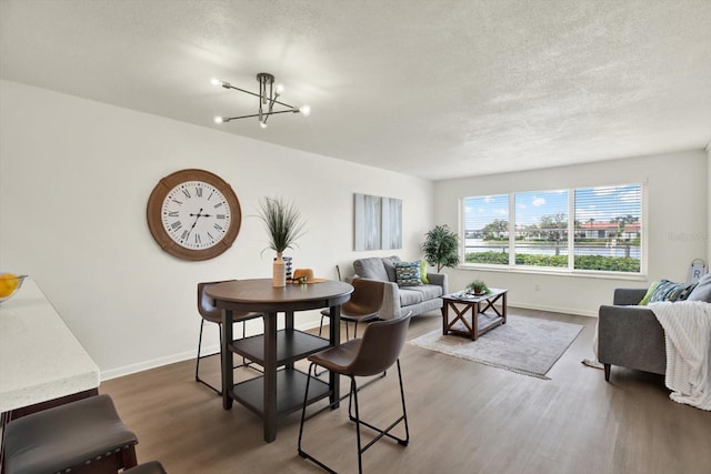 dining space featuring a notable chandelier, a textured ceiling, and dark hardwood / wood-style flooring