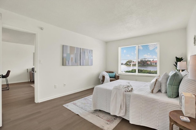 bedroom featuring a textured ceiling and dark hardwood / wood-style flooring