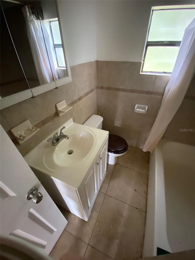 bathroom featuring tile patterned flooring, tile walls, toilet, and vanity