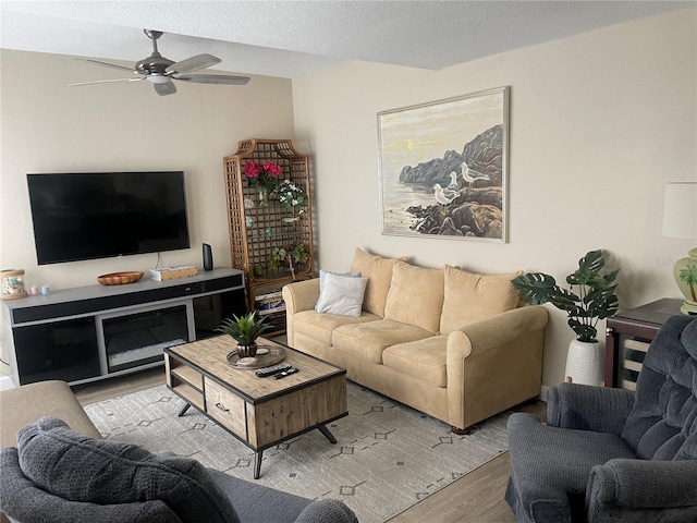 living room with a textured ceiling, ceiling fan, and light hardwood / wood-style floors