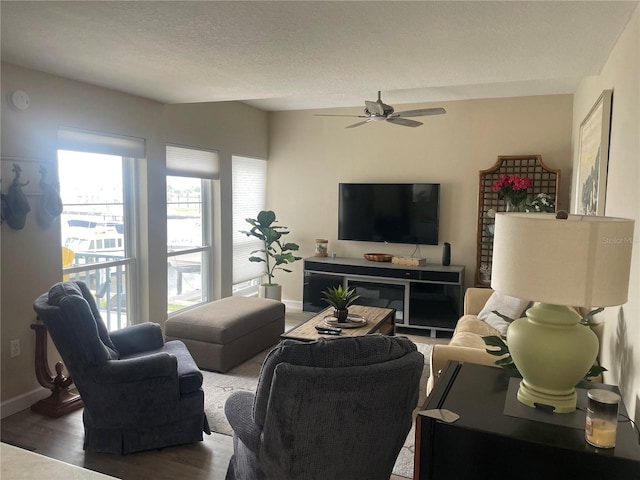 living room with a textured ceiling, wood-type flooring, and ceiling fan