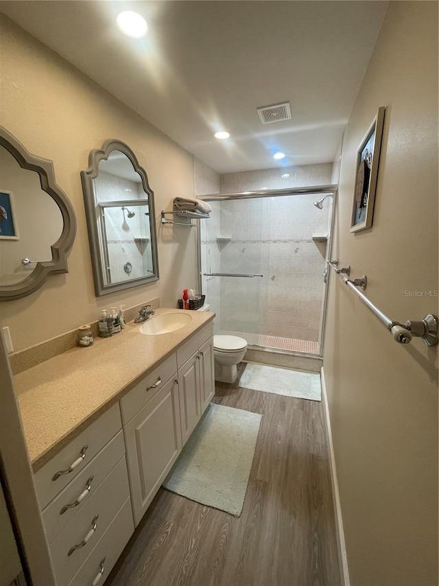 bathroom with an enclosed shower, hardwood / wood-style floors, toilet, and vanity