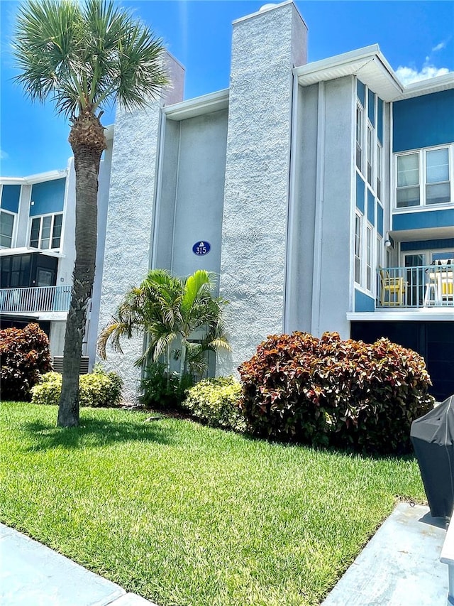 view of side of home with a balcony and a lawn